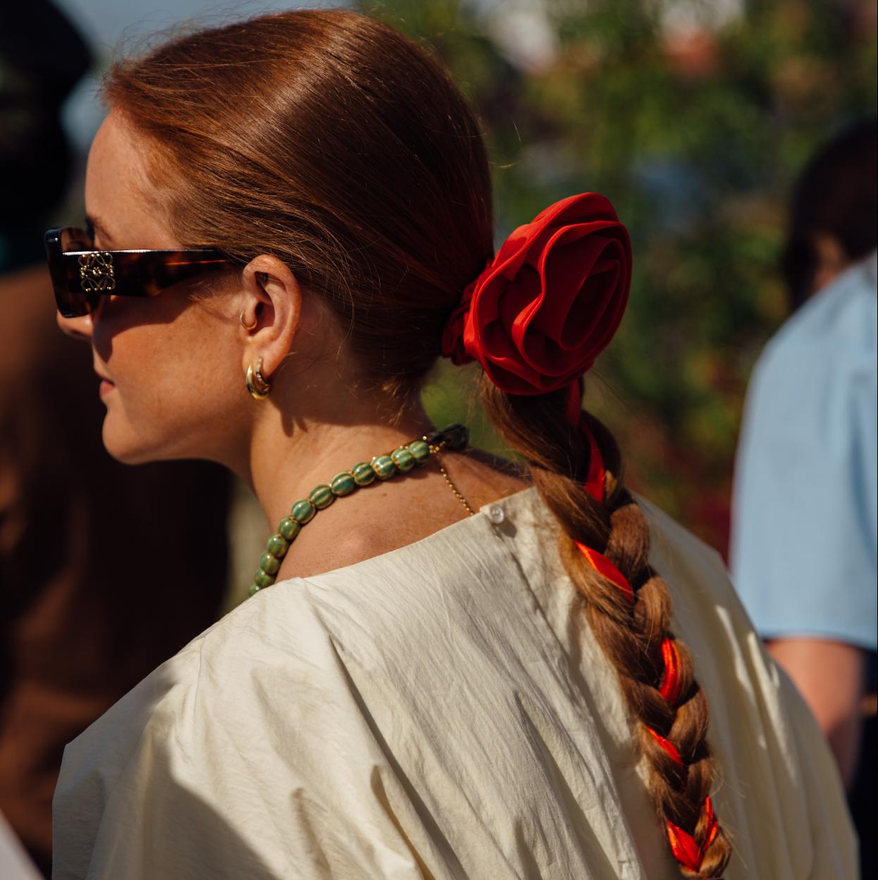 Esta trenza sencilla con una flor roja como protagonista vista en el street style de Copenhague, es uno de nuestros peinados con accesorios favoritos.