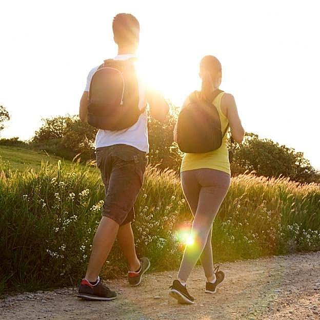 Pareja paseando por el campo con una mochila a la espalda.