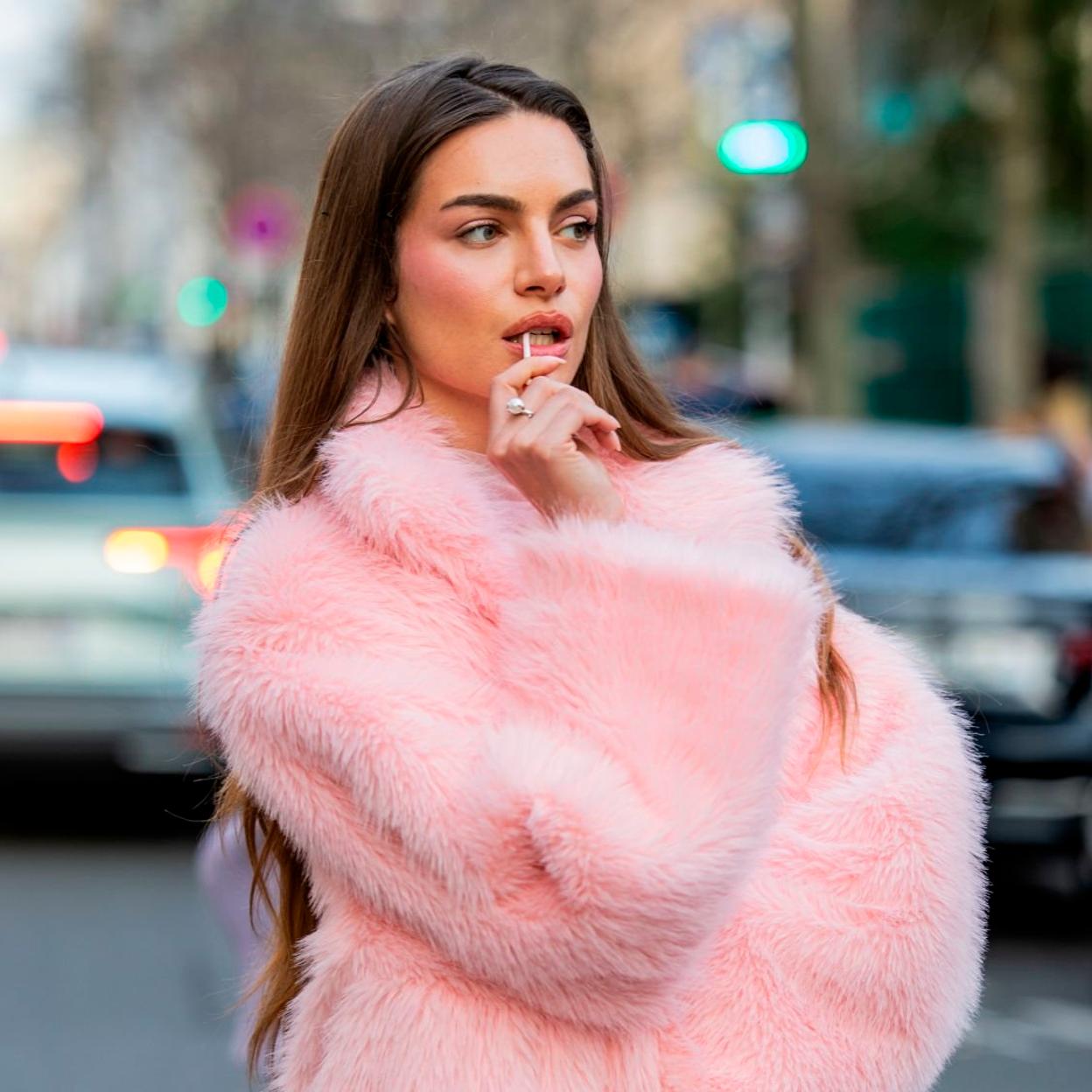 Mujer joven sentada en un puesto de fruta y verdura fresca. 