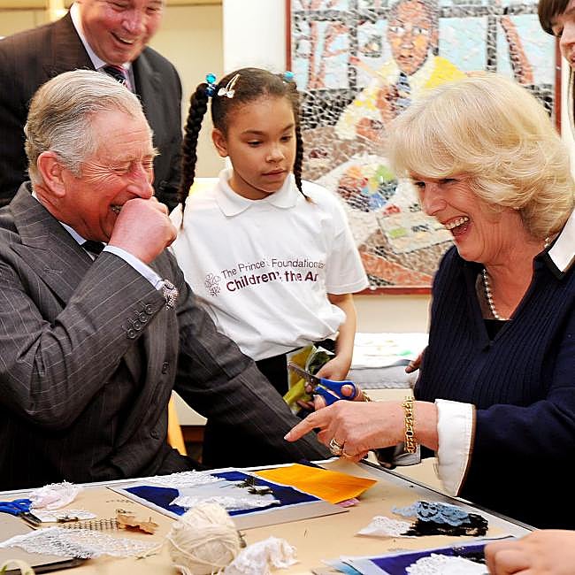Carlos III y Camilla de Inglaterra compartiendo risas en un acto público.