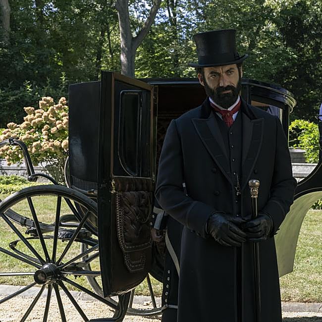 Morgan Spector como George Russell en la secuencia en la que él y Sage abandonan la reunión organizada por J.P. Morgan.