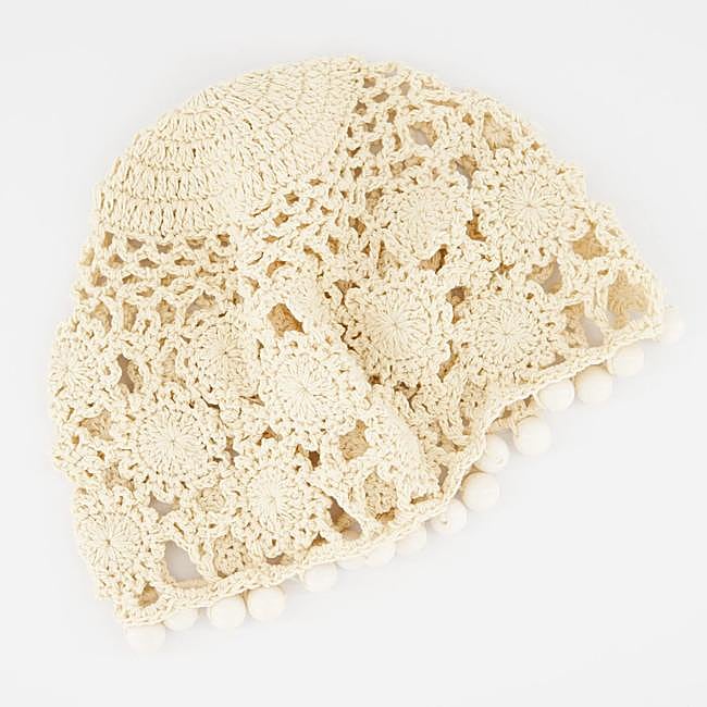 Gorro de croché calado con borlas en beis de Ulanka.