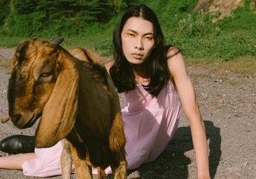 Mujer posando con una cabra en el monte.