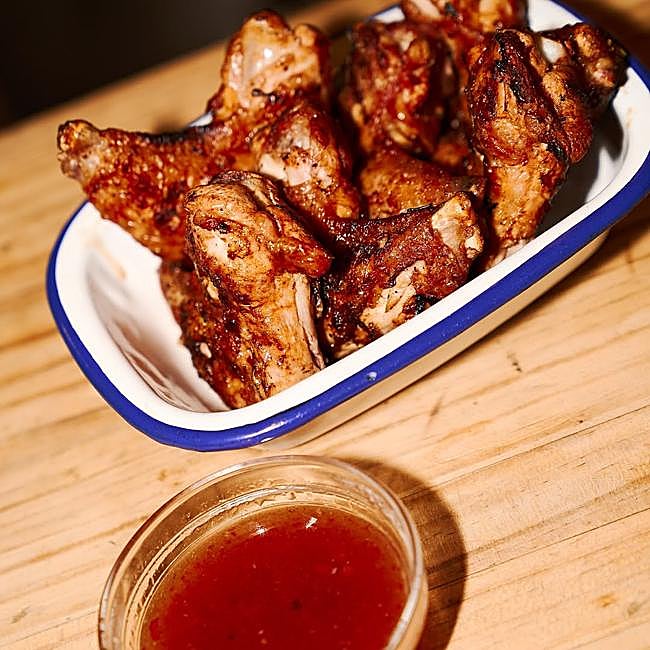 Las alitas, y una de las salsas, de Piri Piri, el lugar perfecto para disfrutar de un buen pollo y verduras a la brasa.