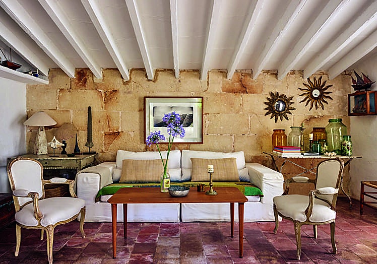 El salón, con espejos en forma de sol, de Candelabro, y fotografía de Lluís Real. El sofá es de Ascensión Latorre y las butacas, de herencia familiar. Los muros son de piedra de marés