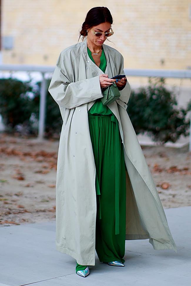 Look de gabardina beige con pantalones verdes.