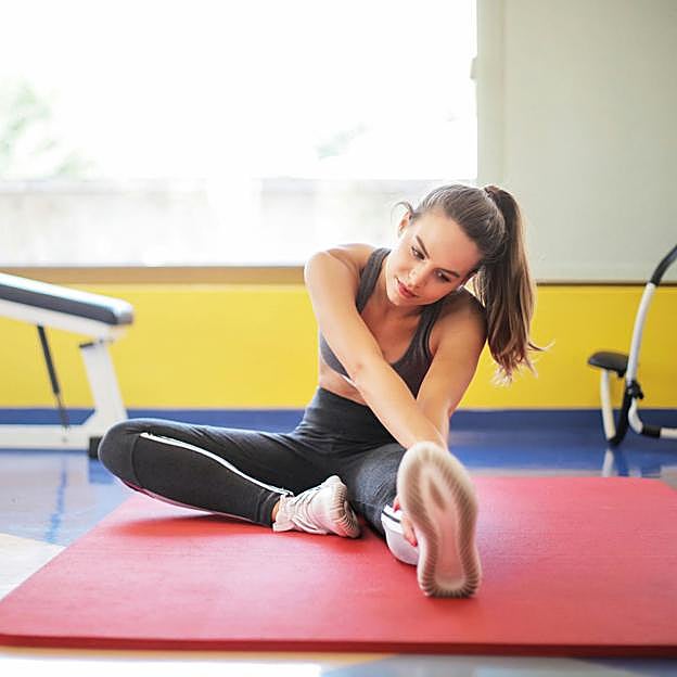 Mujer haciendo ejercicio sobre esterilla. 