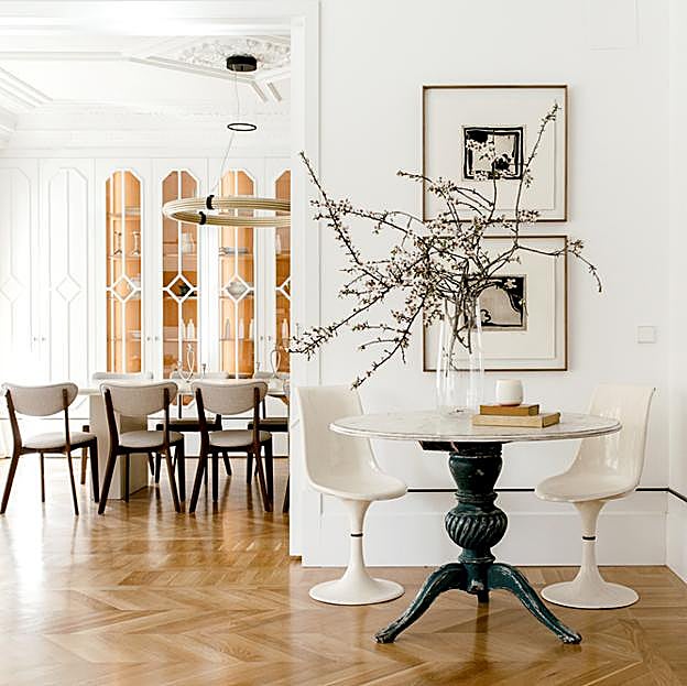 Uno de los salones que firma García Ferrer, con mesa en primer plano de la tienda de muebles antiguos Olofane, sillas Tulip compradas en Wallapop y cuadros de la galería de arte Orellana. Al fondo, alacena acristalada, un diseño a medida del estudio Pilsferrer.