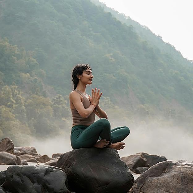 Mujer practicando yoga sobre una roca. 