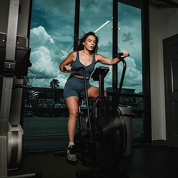 Mujer haciendo bicicleta estática en su gym. 