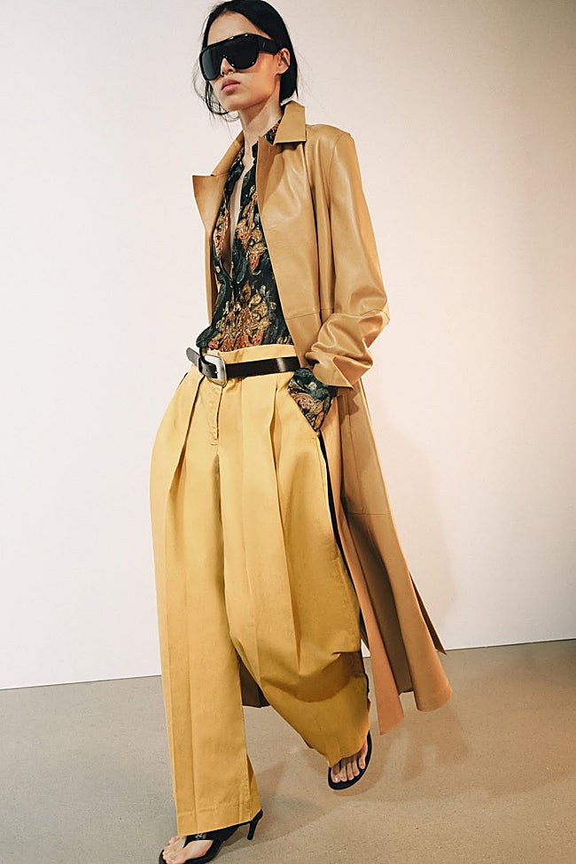 Trench largo + camisa estampada con flores + pantalones con pinzas (Foto: Zara)