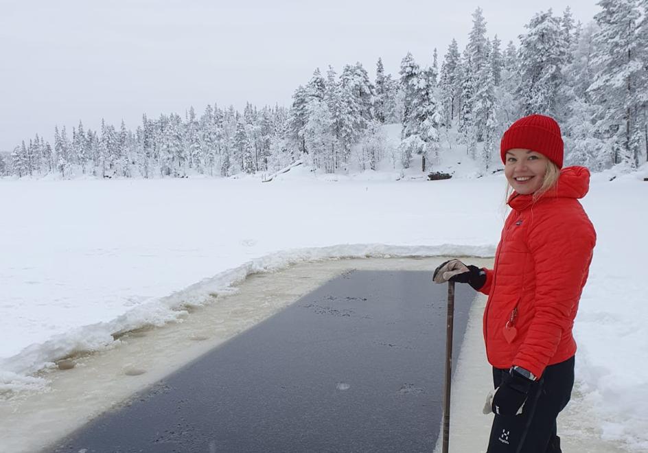 Elina posa junto a una 'piscina' natural de hielo abierta junto a un bosque nevado en la que se dispone a zambullirse.