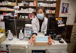 Una farmacéutica muestra una mascarilla durante la pandemia