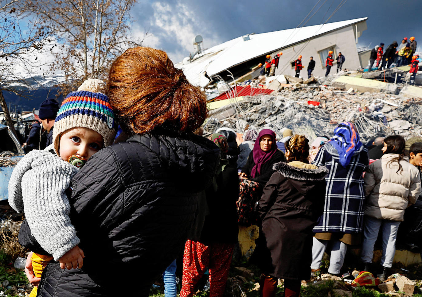 Una mujer sostiene a un niño cerca de los escombros y los daños causados por el seísmo en Gaziantep, Turquía. / SUHAIM SALEM (REUTERS)