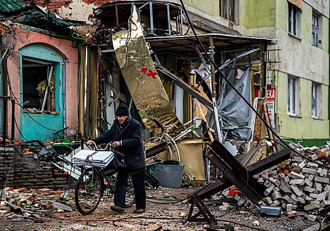 Un ucraniano empuja su bicicleta entre las montañas de escombros de Bajmut