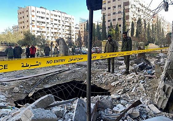 Agentes de policía observan el socavón provocado en una calle de Damasco por los bombardeos.