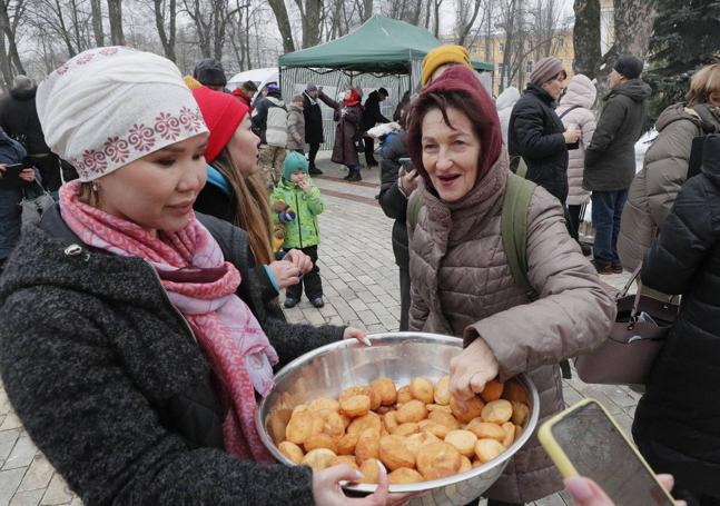 Una mujer kazaja distribuye baursaki, un pan tradicional de su país, a los lugareños cerca de una de las yurtas instaladas en el centro de Kiev para atender a la población.