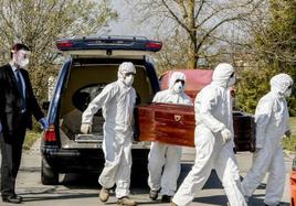 Trabajadores de una funeraria portan el cadáver de un fallecido por covid.