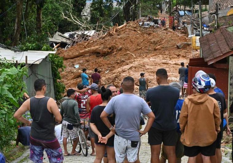 Un grupo de vecinos miran una calle cubierta de lodo en Sao Sebastiao tras las inundaciones