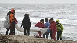 Los equipos de rescate cubren uno de los cadáveres encontrados en la playa de Cutro.