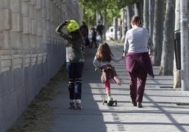 Una madre pasea con sus dos hijas por un parque de Madrid.