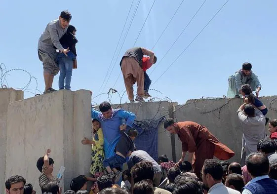 Afganos se agolpan a lo largo del muro del aeropuerto de Kabul para intentar huir del país en agosto de 2021.