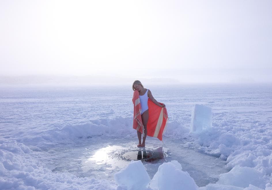 Elina se protege con una toalla tras darse un chapuzón en un 'avanto' abierto en un septentrional lago finlandés.