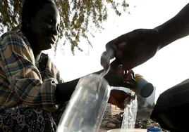 Una niña senegalesa llena unas bolsas con agua potable para venderlas al público en una tienda de una carretera de Dakar, Senegal.