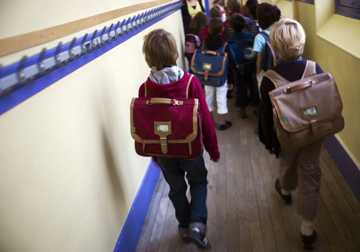 Un grupo de niños se dirige a clase por un pasillo del colegio.