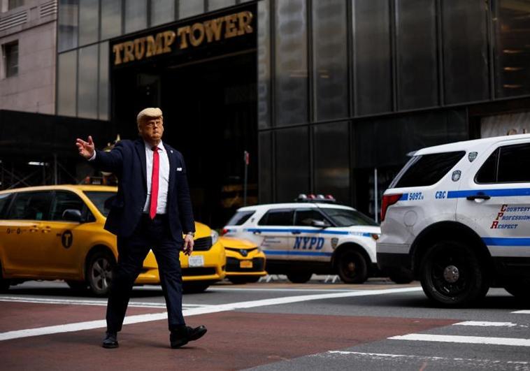 Un hombre con una máscara que representa al expresidente estadounidense camina frente a la Torre Trump, en Manhattan.
