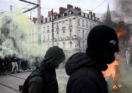 Dos radicales caminan frente a un escenario de destrucción durante una manifestación en Nantes.