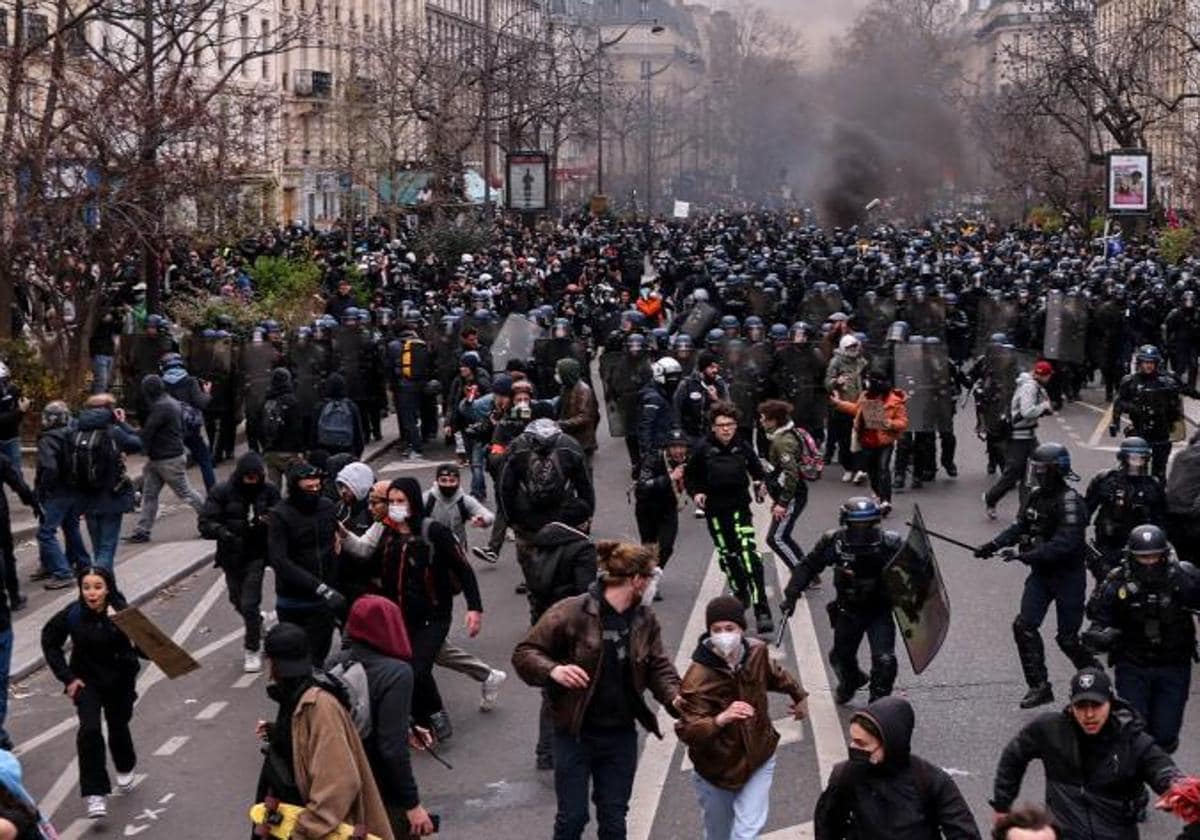 Decenas de manifestantes corren delante de la Policía francesa en París durante una nueva jornada de protestas contra la reforma de las pensiones.