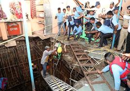 Los equipos de emergencia rescatan a una de las víctimas que cayó en un pozo tras derrumbarse parte de un templo hindú en Indore.