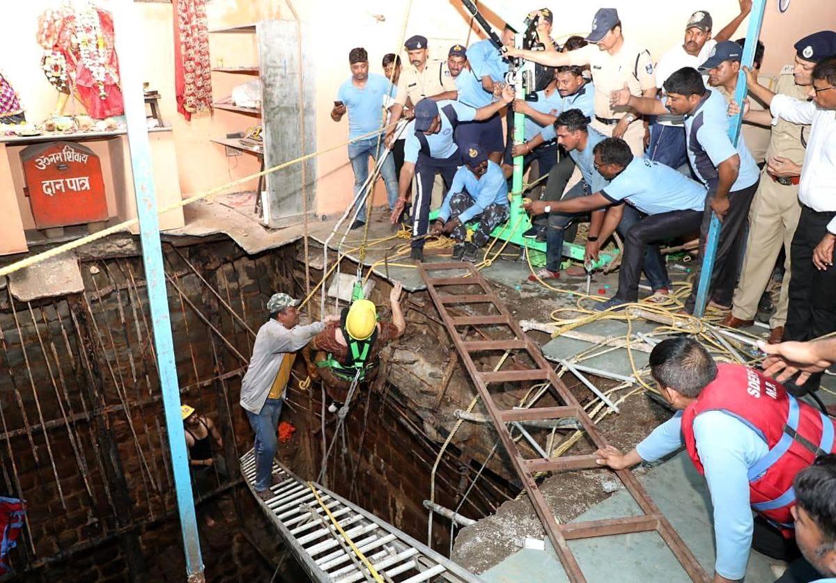 Los equipos de emergencia rescatan a una de las víctimas que cayó en un pozo tras derrumbarse parte de un templo hindú en Indore.