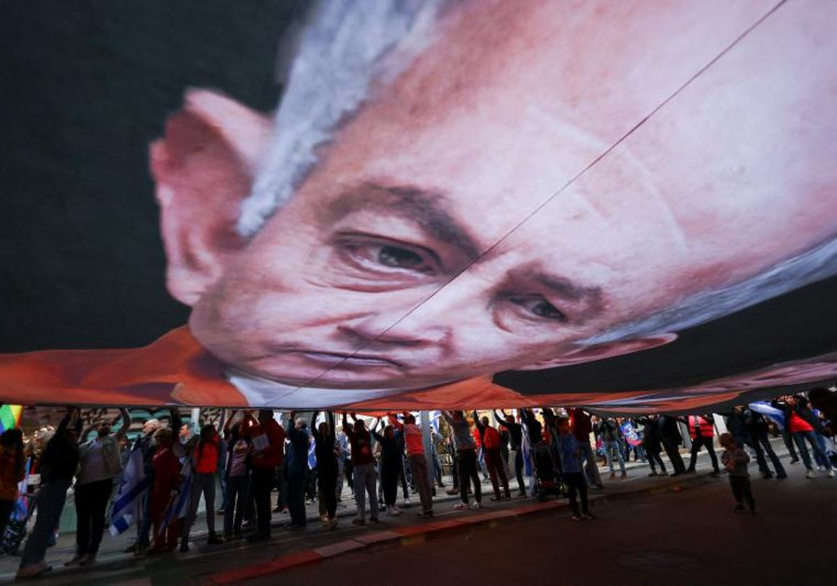 Manifestantes sostienen una gran pancarta con el rostro de Netanyahu durante la manifestación de este sábado contra él y su plan de reforma judicial.