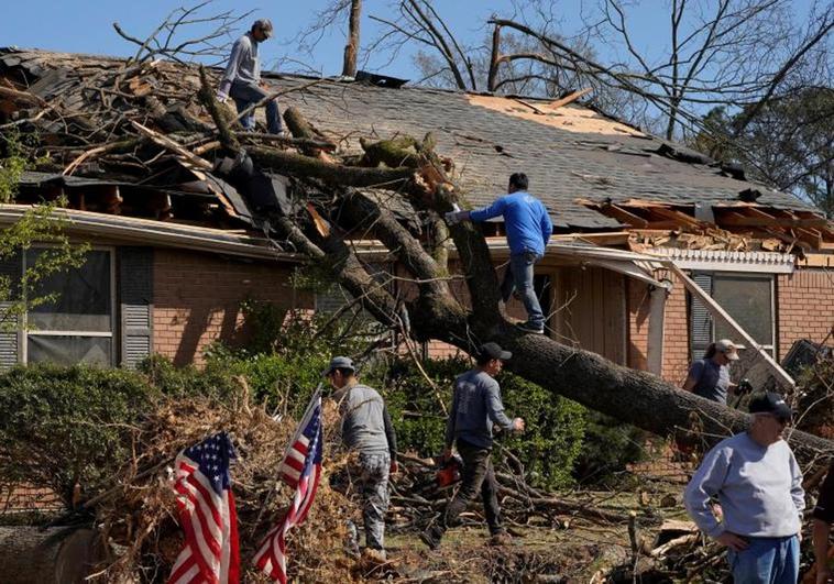 Vecinos intentan retirar un árbol que cayó sobre una vivienda de la localidad de Little Rock, en Arkansas.