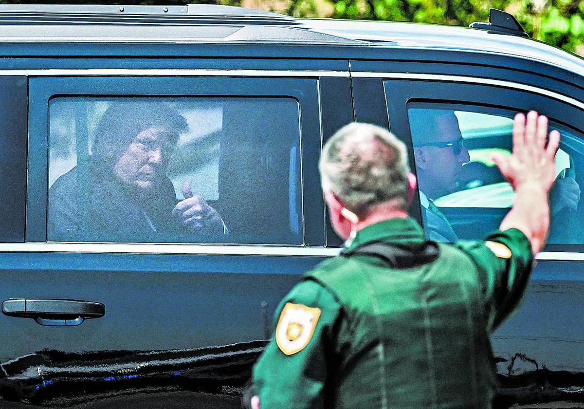 Trump hace el signo de la victoria a un policía que le saluda al paso del convoy de vehículos que este lunes le trasladó al aeropuerto de Palm Beach.