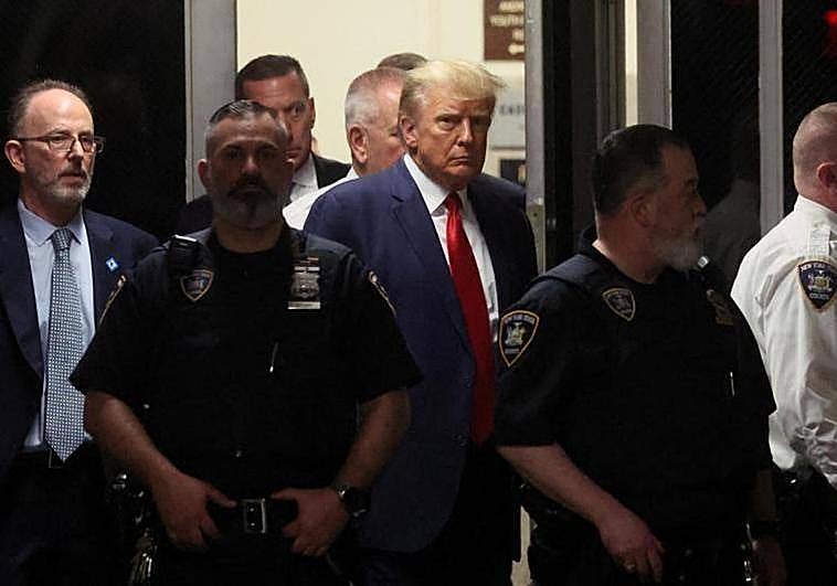 Trump, rodeado de su equipo de asesores legales, se sienta en el banquillo de los acusados.