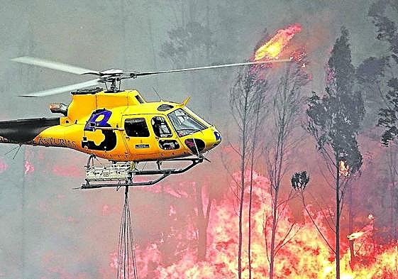 Un helicóptero ayuda en las labores de extinción en un reciente incendio en la localidad asturiana de Toraño.