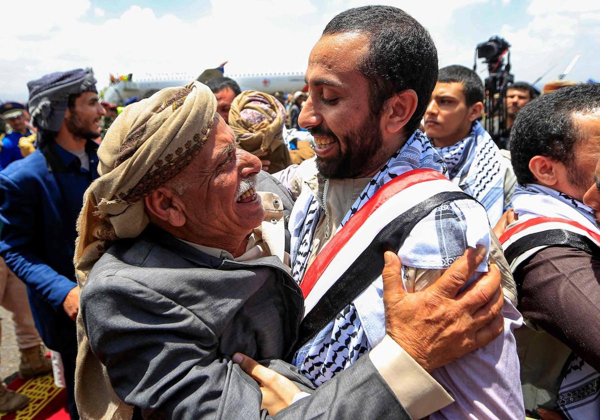 Un anciano abraza a uno de los prisioneros hutíes intercambiados en un acuerdo del Gobierno de Yemen a su llegada al aeropuerto internacional de Sanaa