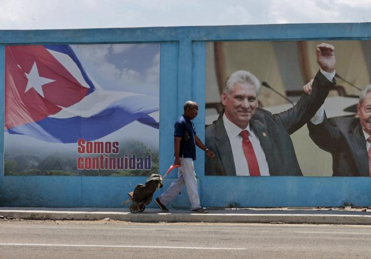 Un hombre camina frente a un fotografía del presidente de la República de Cuba Miguel Díaz-Canel junto a su predecesor, Raúl Castro, en La Habana.