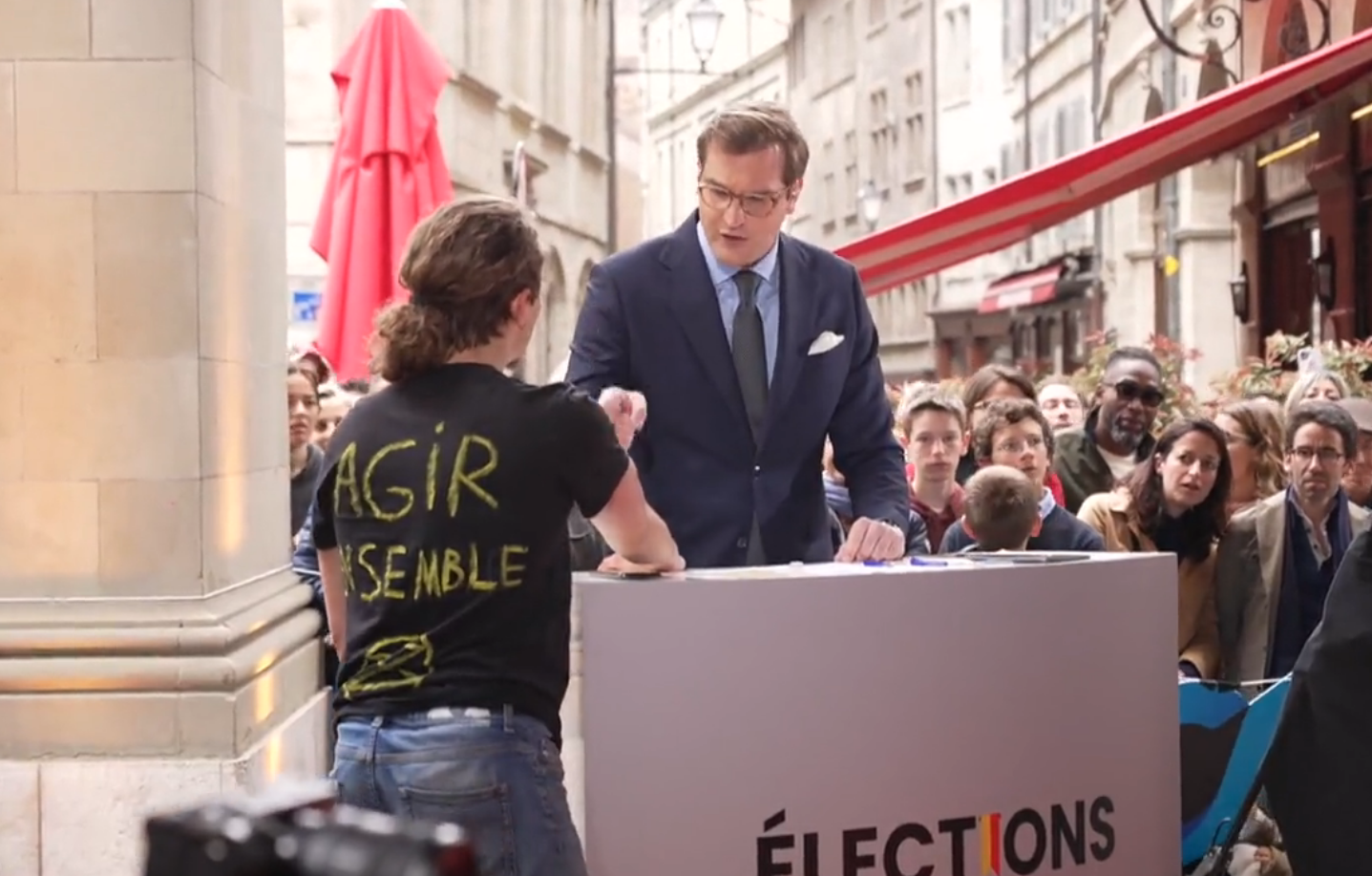 Un ecologista pega su mano al atril de un periodista durante un debate político en Ginebra