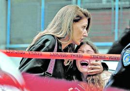 Una madre consuela a su hija en presencia de un policía al ser evacuada del colegio que acogió la matanza.