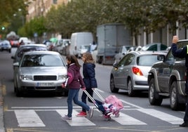 Dos escolares cruzan un paso de peatones próximo a su colegio.