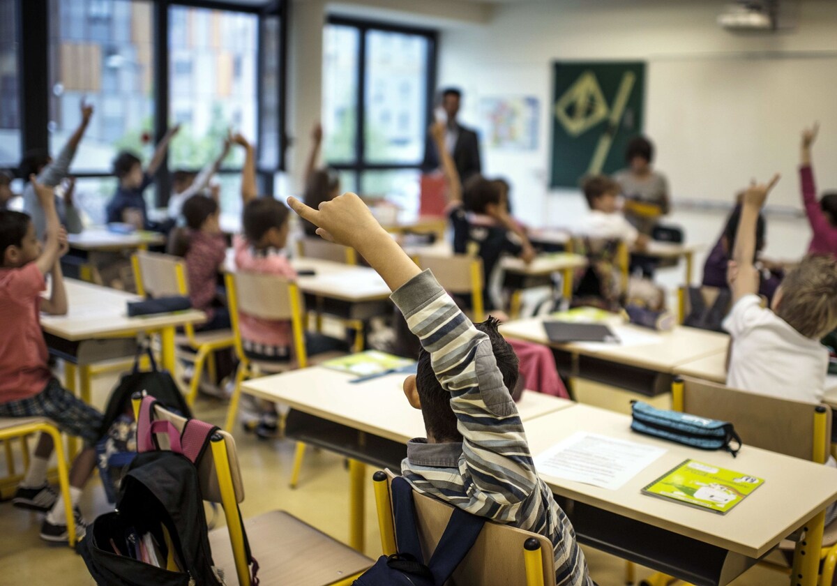 Un grupo de alumnos levantan la mano en clase para contestar a una pregunta.