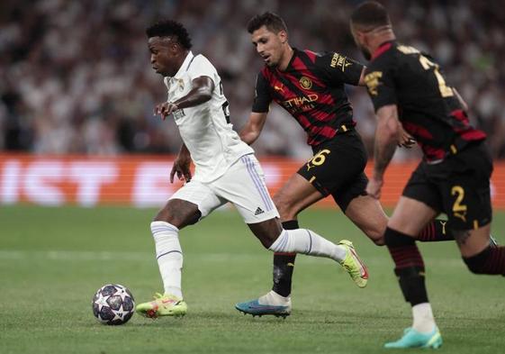 Vinicius conduce el balón perseguido por Rodri y Walker.