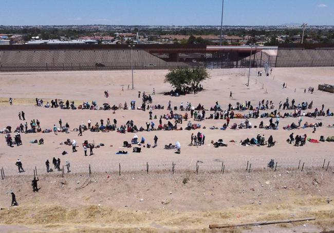 Varias personas esperan frente al muro fronterizo que divide México y EE UU