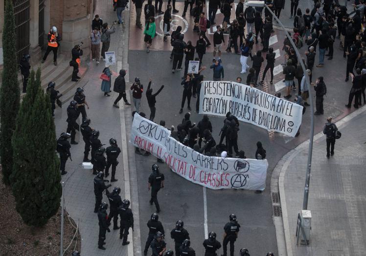 Imagen principal - En la imagen superior los antidisturbios de los Mossos vigilan la marcha prookupación de este jueves en previsión de incidentes violentos; denajo, vista general de la zona de Barcelona donde están situados los inmuebles afectados, la Ruina y el Kubo; por último, detalle de una de las casas okupadas.