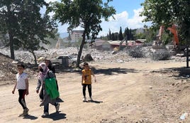 Dos mujeres con sus hijos caminan entre las ruinas de los edificios derribados por el terremoto.