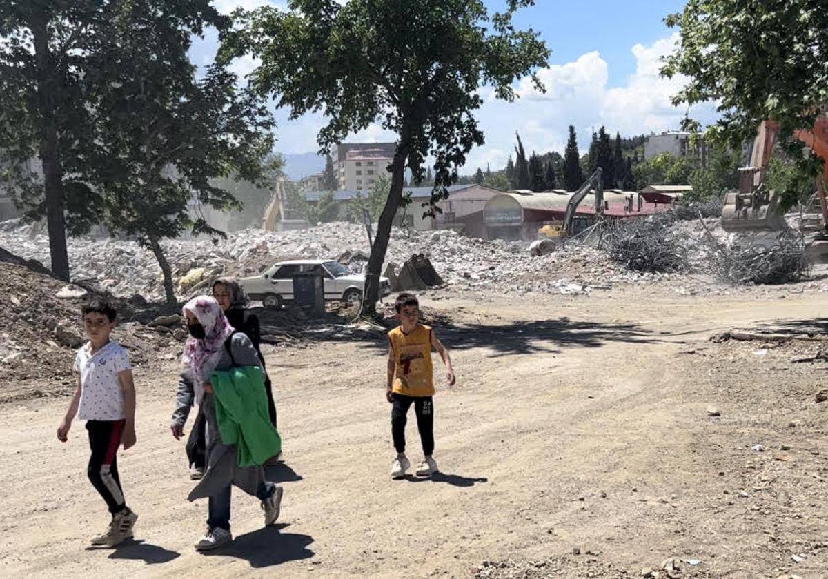 Dos mujeres con sus hijos caminan entre las ruinas de los edificios derribados por el terremoto.